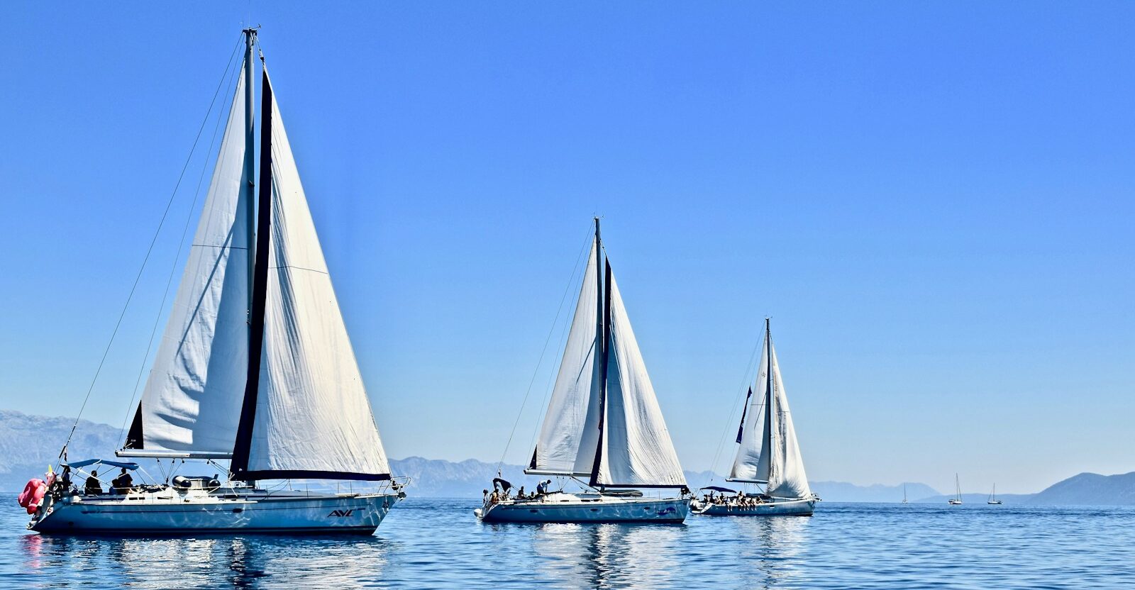 three sail boats on water during daytime