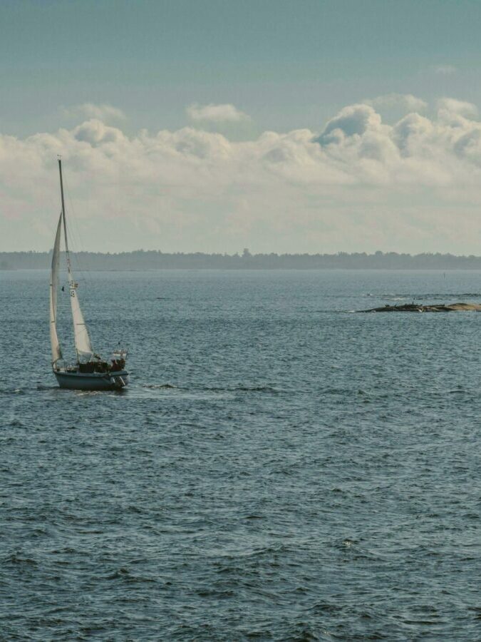 Scenic view of a sailboat cruising through the serene waters of Finland's archipelago region.